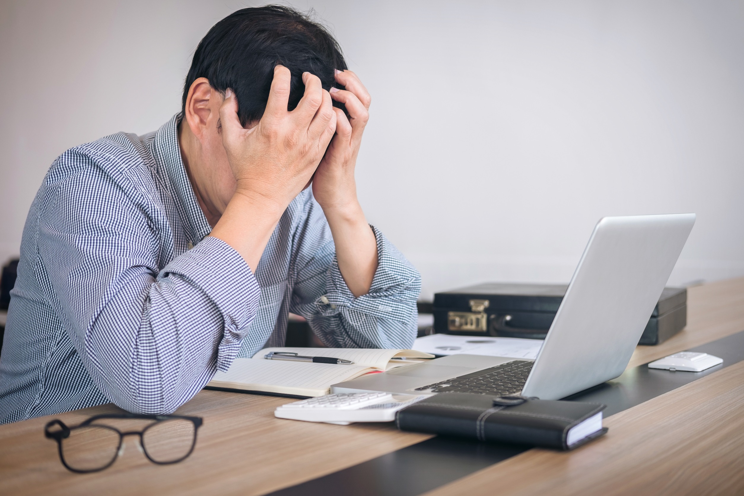 Furstrated businessman sitting at his computer with head in his hand 